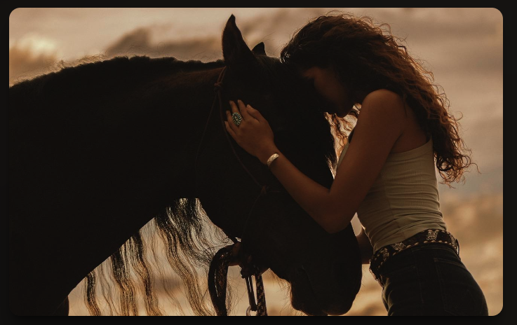 A woman tenderly pressing her forehead against a horse at golden hour